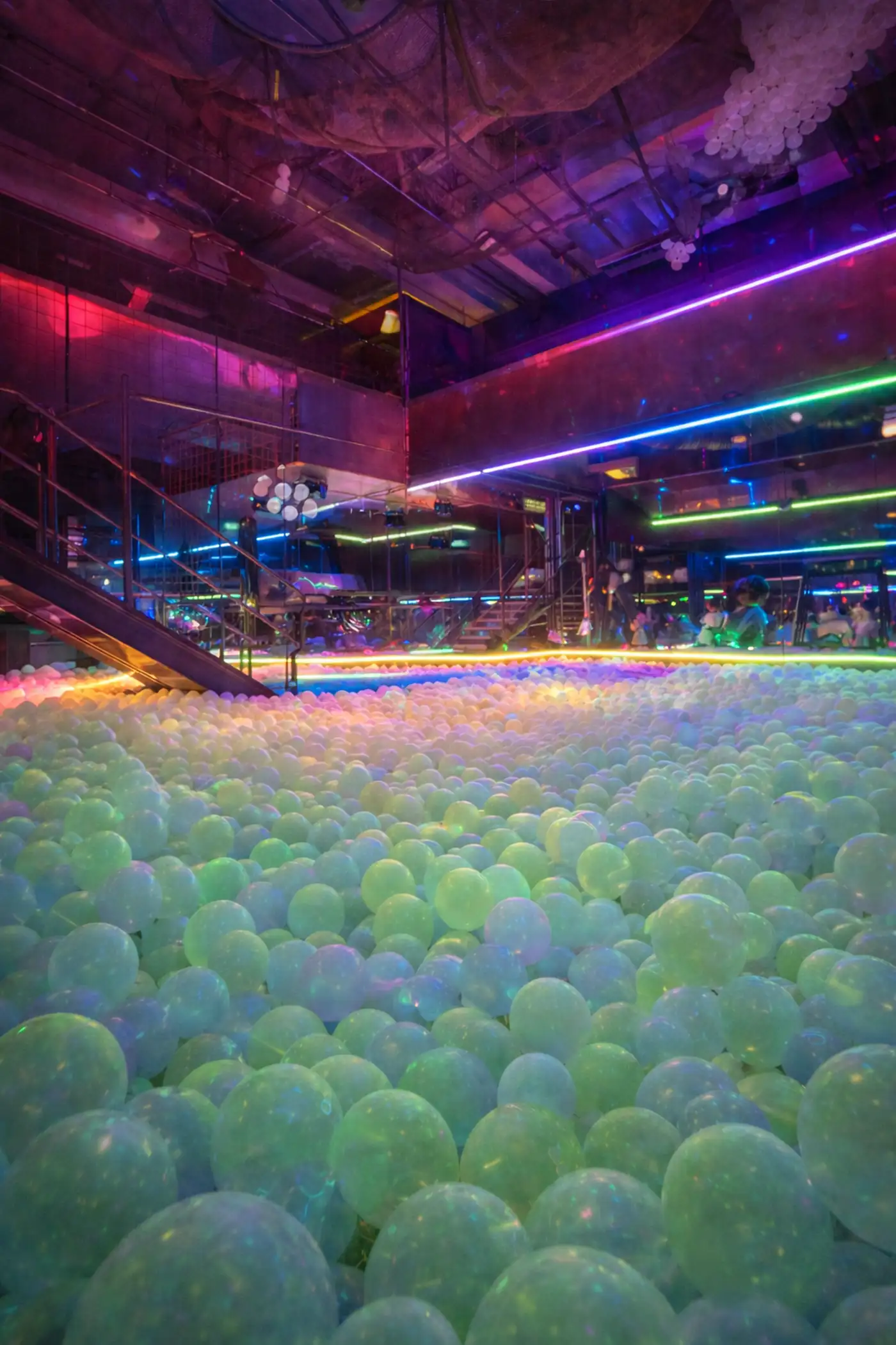 Inside the glowing ball pit at The Drop PHX, lit pastel green and blue under neon